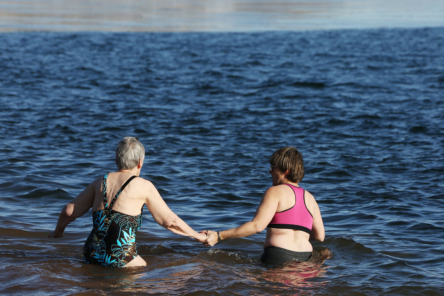 Nancy Wells, left, wades into the water with her daughter Susan
